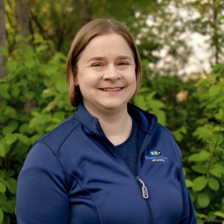 smiling female veterinarian standing in front of greenery