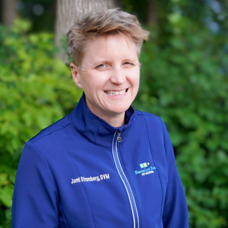 smiling female veterinarian standing in front of forest